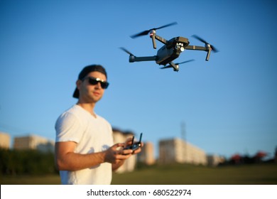 Drohne schwebt vor dem Menschen mit Remote-Controller in seinen Händen. Quad-Kopter fliegt in der Nähe des Piloten. Guy nimmt Luftaufnahmen und Videos auf
