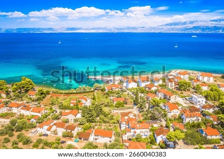 Drone image of Mirca on Brac island showing clustered stone houses, tiled roofs, narrow streets and calm Adriatic shoreline in a quiet Mediterranean village setting under clear sky