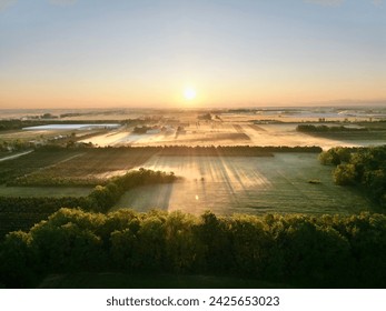 Drone image of the sunrise over fields with low-lying fog