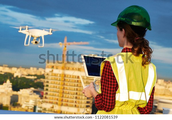 Drone inspection. Operator inspecting\
construction building site flying with\
drone