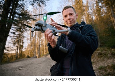 Drone operator holding remote controller and drone in hands. Start flying from the hand. Drone Pilot Releasing Drone camera from its hand. Aerial nature photography and videography.