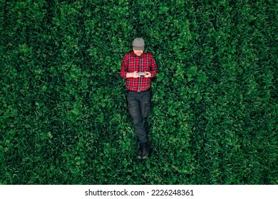 Drone operator, top view of man lying in grass field and using drone remote controller, copy space included