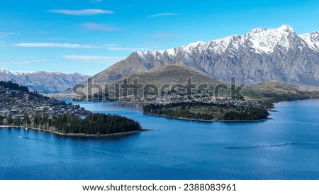 Drone panoramic view of the bays and inlets at Queenstown town at the southern end of Lake Wakatipu with a backdrop of the snow capped Remarkables Mountain range