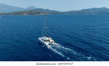 Drone perspective of a catamaran sailing on the open ocean.
