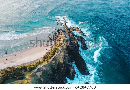 Drone photo from the sky of the most Easterly point of mainland Australia. Dramatic view of Cape Byron Bay, waves crashing into the rocky land.