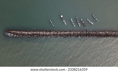 A drone photo of some traditional fishing canoes anchored on a breakwater is suitable for the background.