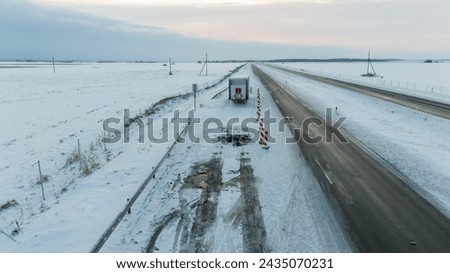 Drone photography of lorry accident site, abandoned trailer and burned up asphalt in a highway during winter cloudy morning