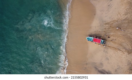 Drone Photography. We See How The Sea Collides With The Stones And Golden Sand Of A Beach In México Leaving Rest Of White Foam. We Can See A Boat Coming In To The Water With A Red Roof.