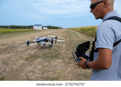 Drone pilot operates handheld controller in open field with drone ready to fly