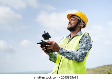 Drone pilot with safety helmet operating drone using remote controller - concept of engineer using drone technology to survey land - Powered by Shutterstock