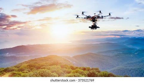 The drone with the professional camera takes pictures of the misty mountains at sunset. Uav drone copter flying with digital camera. Hexacopter drone with high resolution digital camera on the sky. - Shutterstock ID 373521769
