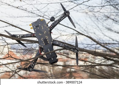 Drone quadcopter accident scene, UAV filming Quadrocopter crashed on tree in city park