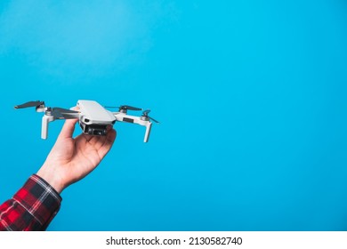 Drone quadcopter held with a hand in clear blue background studio. Concepts of drone pilot lessons and aerial photography - Powered by Shutterstock