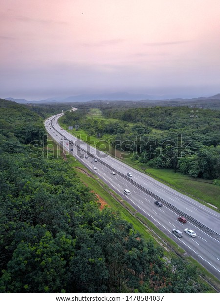 Drone shot of a beautiful highway\
in Malaysia PLUS Highway over nice sunset scenery in\
dusk