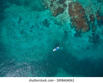 Drone shot of a boat floating near the coral reef barrier Cancun Sardinia rent boat for tourism in summer - Powered by Shutterstock