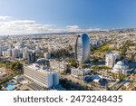 Drone shot of a bustling Limassol cityscape with a distinctive elliptical glass tower on a clear day. Cyprus