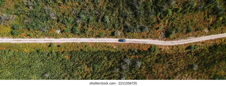 Drone Shot Of A Car Driving On A Dirt Road On A Mountain In A Forrest. Panoramic.