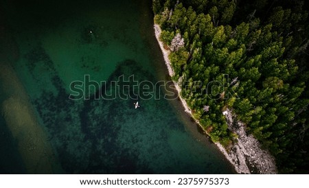 drone shot of kayak fishing beside island in a lake