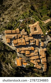 A drone shot looking directly down at terracotta tiles, narrow walkways, and small garden courtyards.