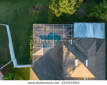 A drone shot of a modern house with a glass pool screen enclosure