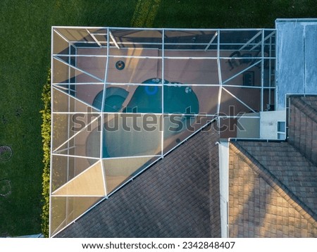 A drone shot of a modern house with a glass pool screen enclosure