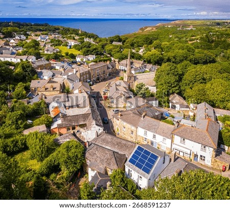 Drone shot over St Agnes, Cornwall, showcasing historic village homes, church, and coastal surroundings—great for travel, real estate, and rural lifestyle visuals