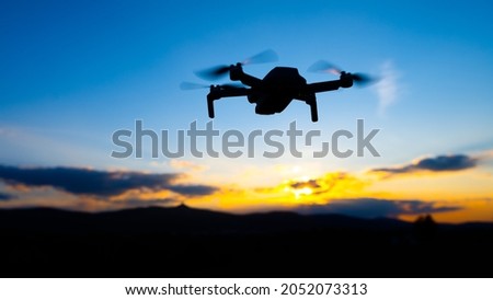 Drone silhouette at sunset time. Unmanned aerial vehicle, UAV, or uncrewed aerial vehicle.