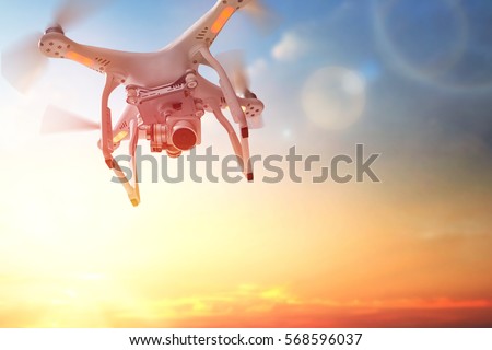 The drone in the  sunset sky. Close up of quadrocopter outdoors.