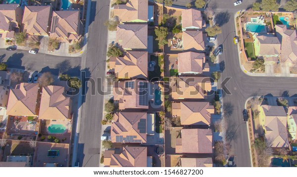 DRONE, TOP DOWN: Flying row houses in a luxury\
suburban neighborhood in Nevada. Cinematic shot of terraced houses\
and backyards in the sunny suburbs of Las Vegas. Empty streets of\
American suburbia.