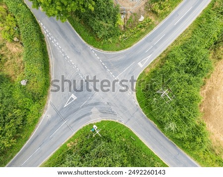 Drone top down view of a dangerous British crossroads seen in a rural location. A nearby blin bend makes this crossing hazardous.