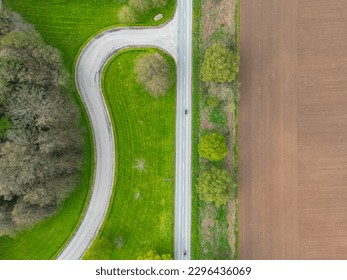 Drone top down view of a pair of motorcyclists seen on a deserted road. A road junction curves away to a hotel complex. - Powered by Shutterstock