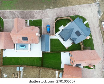 Drone top down view of recently built expensive detached family homes. A large conservatory and glass lantern is seen on the left.