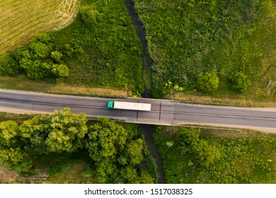 Drone Top Down View Of Truck Driving Remote Road Over Small River During Summer Day.