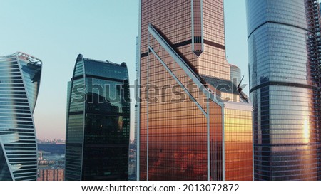 Drone vertical flight among the modern skyscrapers in Moscow City business centre, sunset reflection in shiny glass facade