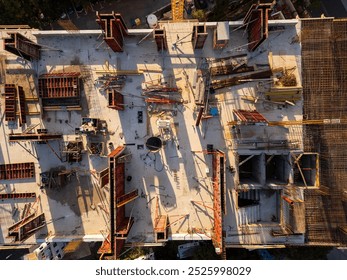 A drone video showcasing a top-down view of a construction site. The image captures the building's foundation, scaffolding, and materials, highlighting the early stages of architectural development