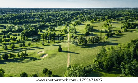 A tranquil aerial view of a lush golf course fairway, bathed in the warm glow of sunset. Ideal for themes of relaxation, nature, and sports, this image captures the peaceful beauty of the golfing experience.