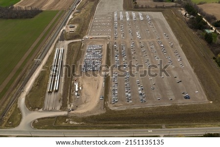 A drone view beside an auto distribution and homologation center. Autotrack train cars sit beside the large center, next to a railway.