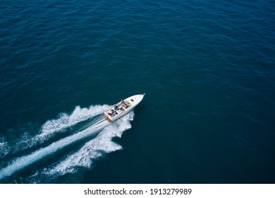 Drone view of a boat sailing across the blue clear waters. Top view of a white boat sailing to the blue sea. Motor boat in the sea. Travel - image.