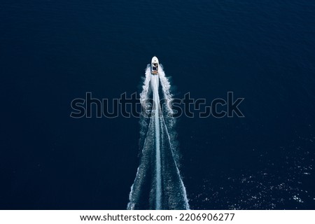 Drone view of a boat sailing. Top view of a white boat sailing to the blue sea. Motor performance boat in the sea. Travel - image. Large white boat fast movement on blue water aerial view.