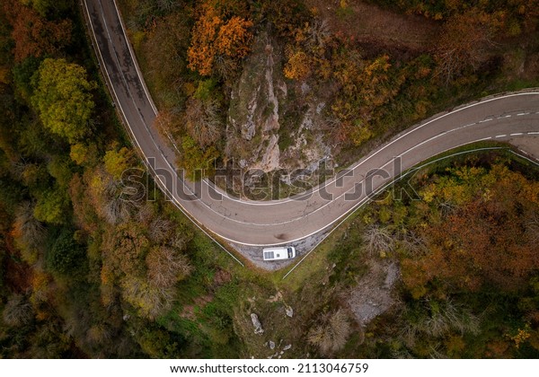 Drone view of a camper van with\
solar panels on a road on a mountain landscape during\
Autumn