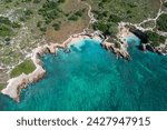 Drone view of coastline sea with clear water washing rocky coast of island with green plants on summer day