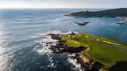 Drone View Of A Golf Course Next To The Ocean With Waves Hitting The Rocks On The Seashore
