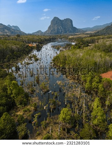 Drone view of the Klong Root Canal near Krabi, Thailand. Mountains in the distance. Nature and greenery all around. Kayaks float along the canal