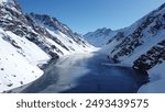 Drone view of Laguna del Inca in winter, located in the Andes Mountains of Chile, showcasing the frozen lake and surrounding snowy peaks