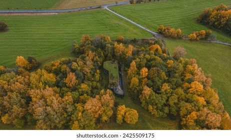 Drone view of landscape with meadows, path and with colourful forest with hidden abandoned concrete bunekr.