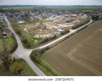 Drone view of a large housing development site being constructed at the edge of the established village of Blackmore, Essex, UK. Seen near a rural crossroads.