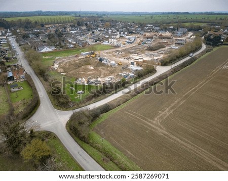 Drone view of a large housing development site being constructed at the edge of the established village of Blackmore, Essex, UK. Seen near a rural crossroads.