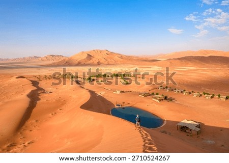 drone view of a man walking in Empty Quarter Rub' al-Khali desert. Desert camp in the sand at dawn. Travel adventure and solitude in land of Oman Rub al-Khali desert