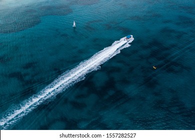 Drone View Of Motor Speedboat With Wake, Kayak And Sailing Boat In Turquoise Caribbean Sea