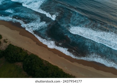 Drone view of ocean rip current, beach with waves in Java at sunset